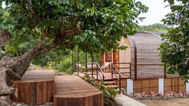 A wooden cabin with a curved roof, surrounded by lush greenery and a stone pathway. - Siquijor Summit Resort (Lazi)