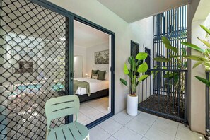Ein Zimmer mit Bett, Sessel, Topfpflanze und Blick auf einen Pool.