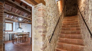 Ein rustikales Interieur mit freiliegenden Backsteinwänden, einer Holztreppe und einem Essbereich mit Tisch und Stühlen.