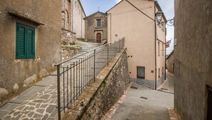 Eine schmale Gasse mit einer Steintreppe, die zu einem Gebäude mit einer roten Tür führt.