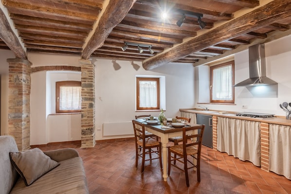 Una cocina con techo de madera, una mesa de comedor con sillas, un ventanal y una estufa empotrada.