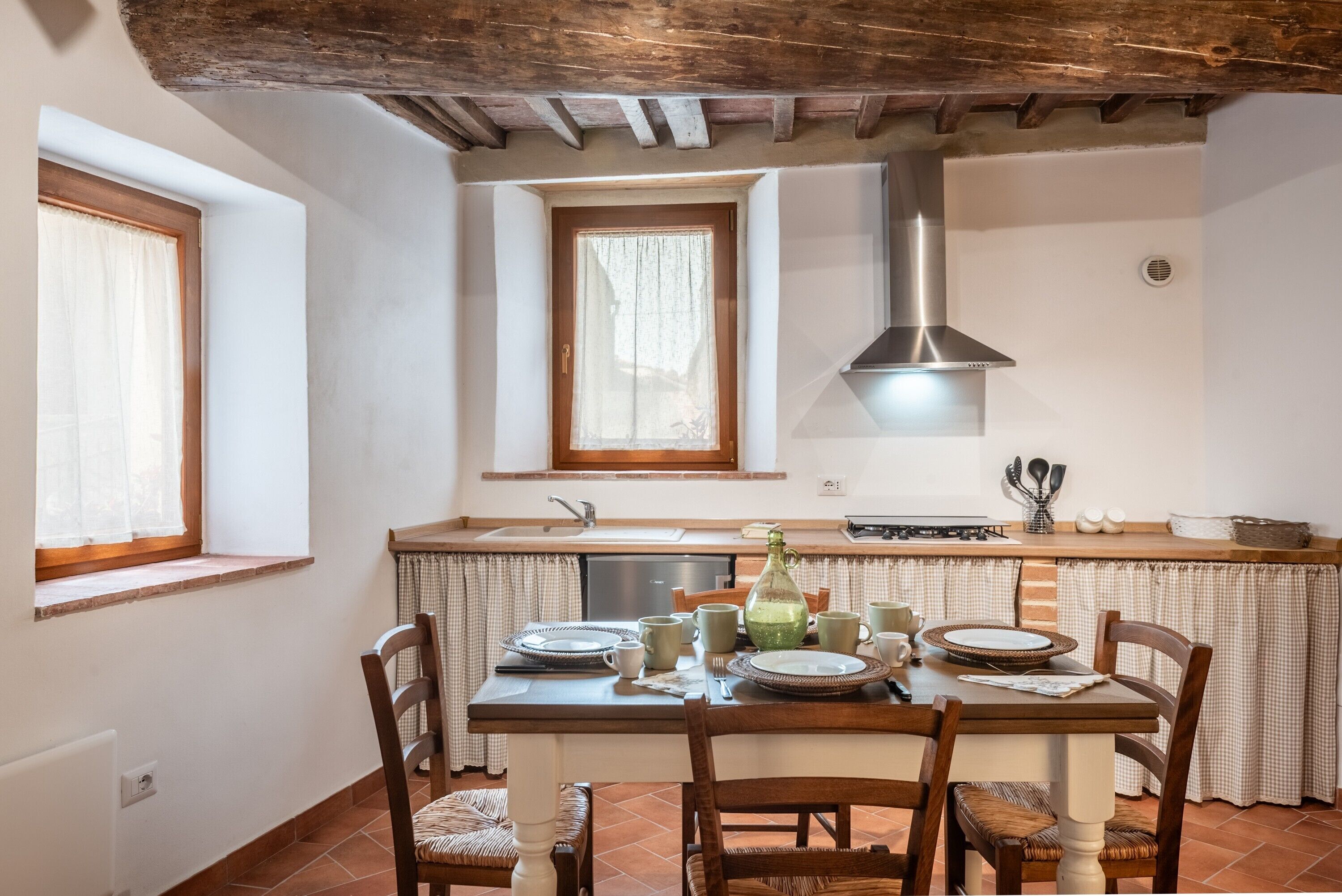 Una cocina con una mesa de comedor para cuatro personas, una ventana y una estufa integrada.