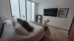 Quarto com uma cama, televisão e janela.