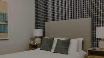 A neatly made bed with two pillows, a bedside table with a lamp, and a wall with a grid pattern.