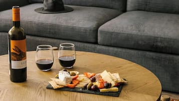 A round wooden table with a charcuterie board, two glasses of red wine, and a bottle of wine.