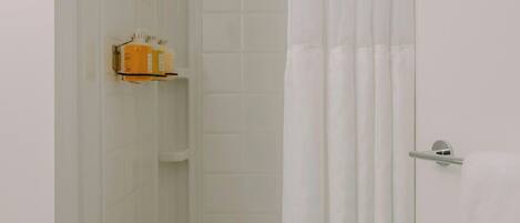 A bathroom with white tiled walls, a shower curtain, and a towel rack.