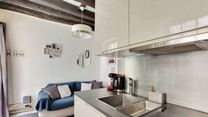 A modern kitchen with stainless steel appliances, a built-in sink, and a compact layout. - Charming Marais Historic Studio (Paris)
