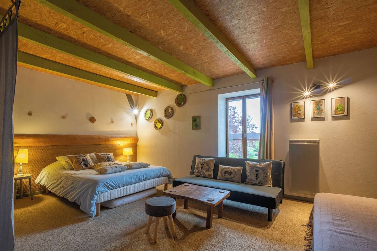 Una habitación acogedora con cama, sofá, una mesita y ventana con cortinas.