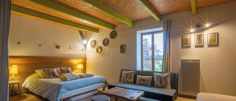 A cozy room with a bed, a sofa, a small table, and a window with curtains.