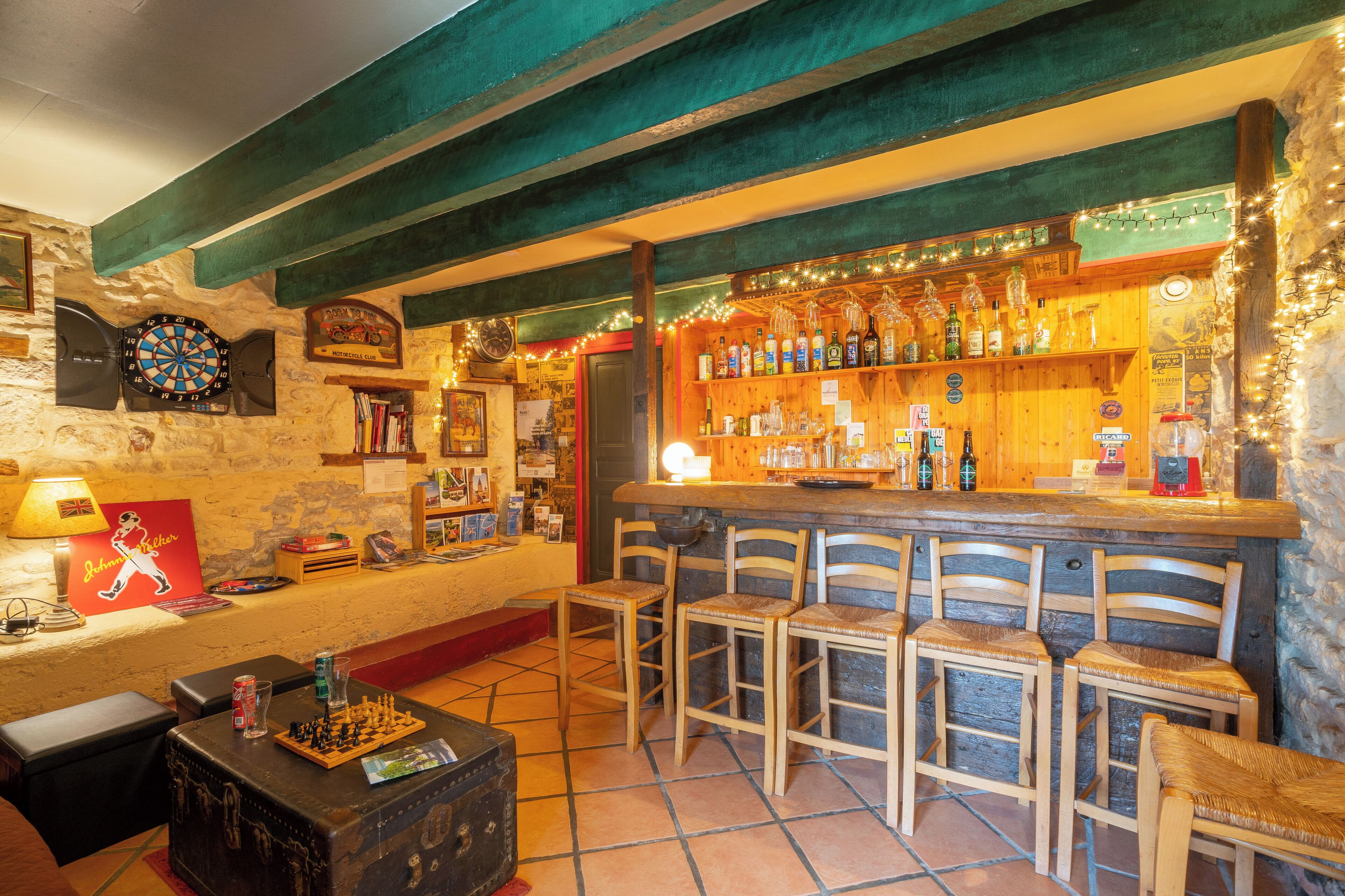 A bar area with wooden chairs, a dartboard, and shelves of liquor bottles.