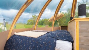 Une pièce confortable avec un lit, une commode en bois et une vue sur l’extérieur.