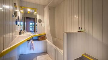 Un baño con una decoración en blanco y amarillo, un lavamanos, una bañera y un espejo.