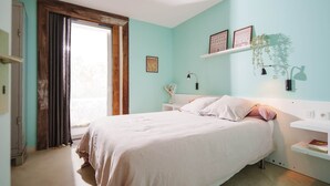 A bedroom with a bed, a nightstand, a shelf with a plant, and a window with curtains. - Gîte La Schlàppe / 3 persons (HERRLISHEIM PRES COLMAR)