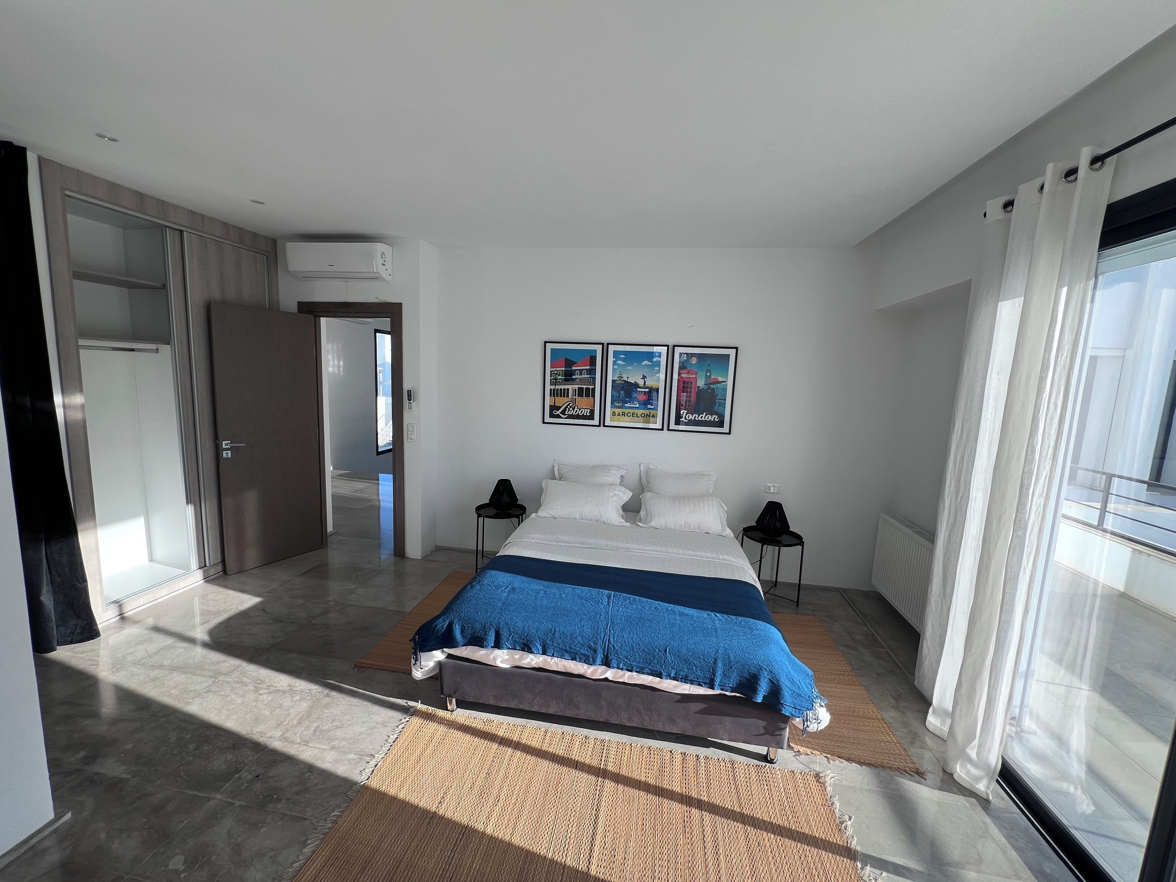 Una habitación de hotel moderna con una cama grande, un televisor de pantalla plana y obras de arte que representan ciudades.