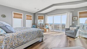 Ein Schlafzimmer mit Bett, Stuhl, Schreibtisch und Meerblick.