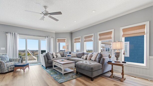 A spacious living room with a sectional sofa, a coffee table, and a ceiling fan. - Renovated Ocean Front Dream House in Sunset Beach (Sunset Beach)