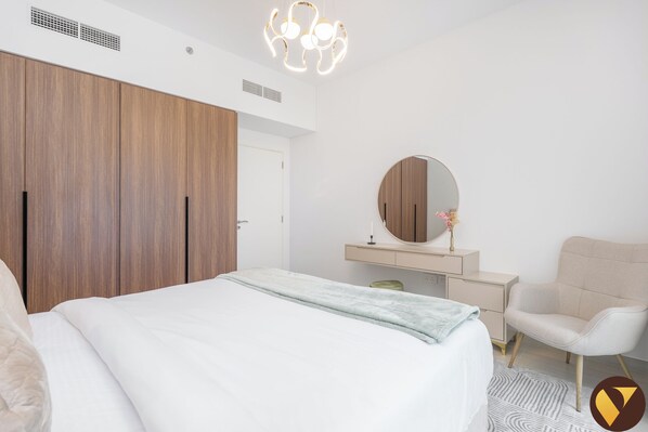 A bedroom with a bed, a wardrobe, a vanity with a mirror, and a chair. - Vogue | Jadeel Madinat Jumeirah near Burj Al Arab (Dubai)