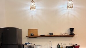 Een moderne keuken met een zwarte koelkast, houten kastjes, een aanrecht met een koffiezetapparaat, een broodrooster en een spoelbak.