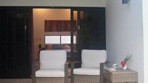 Een moderne patio met twee rieten stoelen, een kleine tafel en een decoratieve vaas.