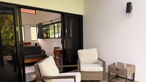Een moderne kamer met een schuifglasdeur naar een balkon, rieten meubels en een klein tafeltje met twee mokken.