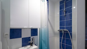 Un baño con ducha, lavamanos y espejo.