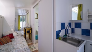 Un dormitorio con cama, almohadas, una mesita de noche y vista al baño.