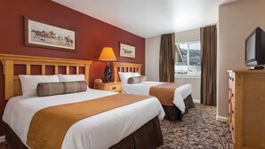 A hotel room with two beds, a wooden headboard, a nightstand with a lamp, a dresser, and a television. - Spacious  2-bedroom condo in beautiful Steamboat Springs  CO. (Steamboat Springs)