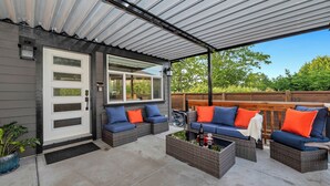 A covered patio area with wicker furniture and a view of the backyard. - Knockan Hill Rentals - Garden Suite (Victoria)