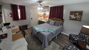 A bedroom with a bed, bedside table, lamp, and a wall clock. - Bluff City Studio: B (Millington)