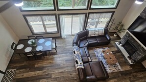 A spacious living area with a sectional sofa, a dining table with placemats, and a fireplace. - BEAUTY AND PRIVACY LIKE NO OTHER!   WALK TO LAKE.  CLOSE TO EVERYTHING POCONOS! (Jim Thorpe)