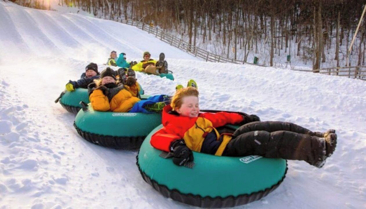 Mensen glijden op sneeuwbanden een besneeuwde helling af.