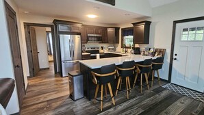 A modern kitchen with dark wooden cabinets, stainless steel appliances, and a central island with bar stools. - BEAUTY AND PRIVACY LIKE NO OTHER!   WALK TO LAKE.  CLOSE TO EVERYTHING POCONOS! (Jim Thorpe)