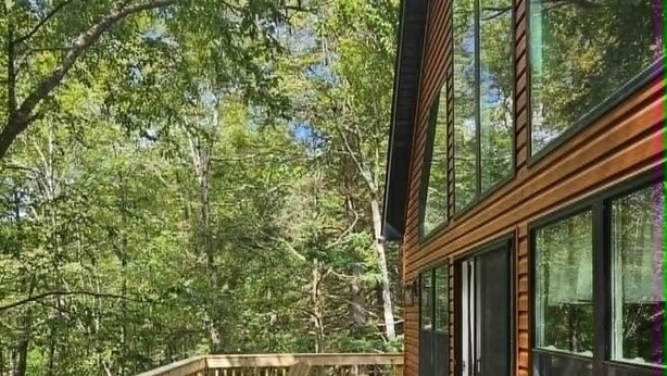 A wooden deck with picnic tables and a view of a forested area. - BEAUTY AND PRIVACY LIKE NO OTHER!   WALK TO LAKE.  CLOSE TO EVERYTHING POCONOS! (Jim Thorpe)