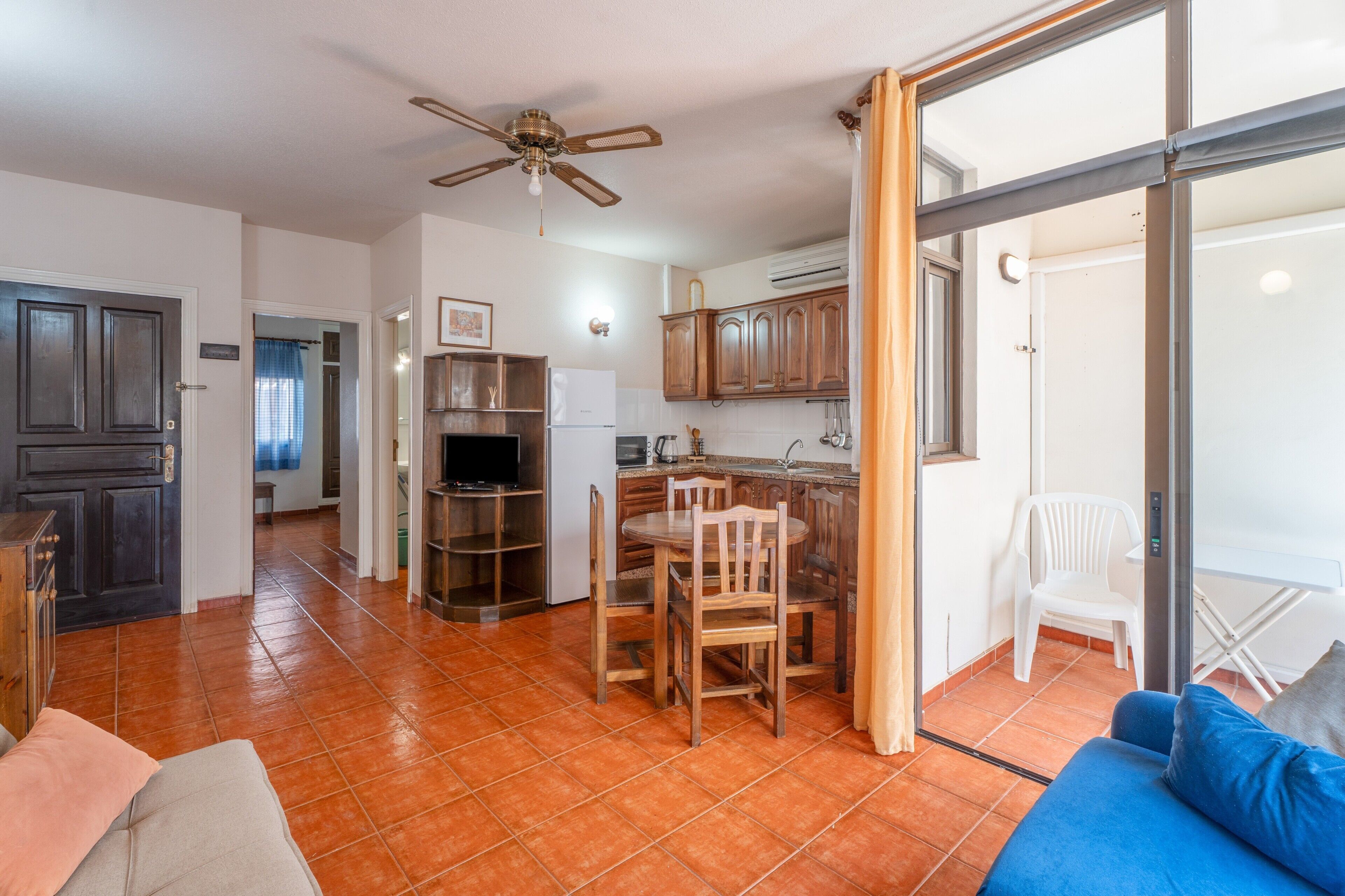 Un espace de vie compact comprenant un coin repas, une kitchenette et une porte-fenêtre coulissante donnant sur un balcon.