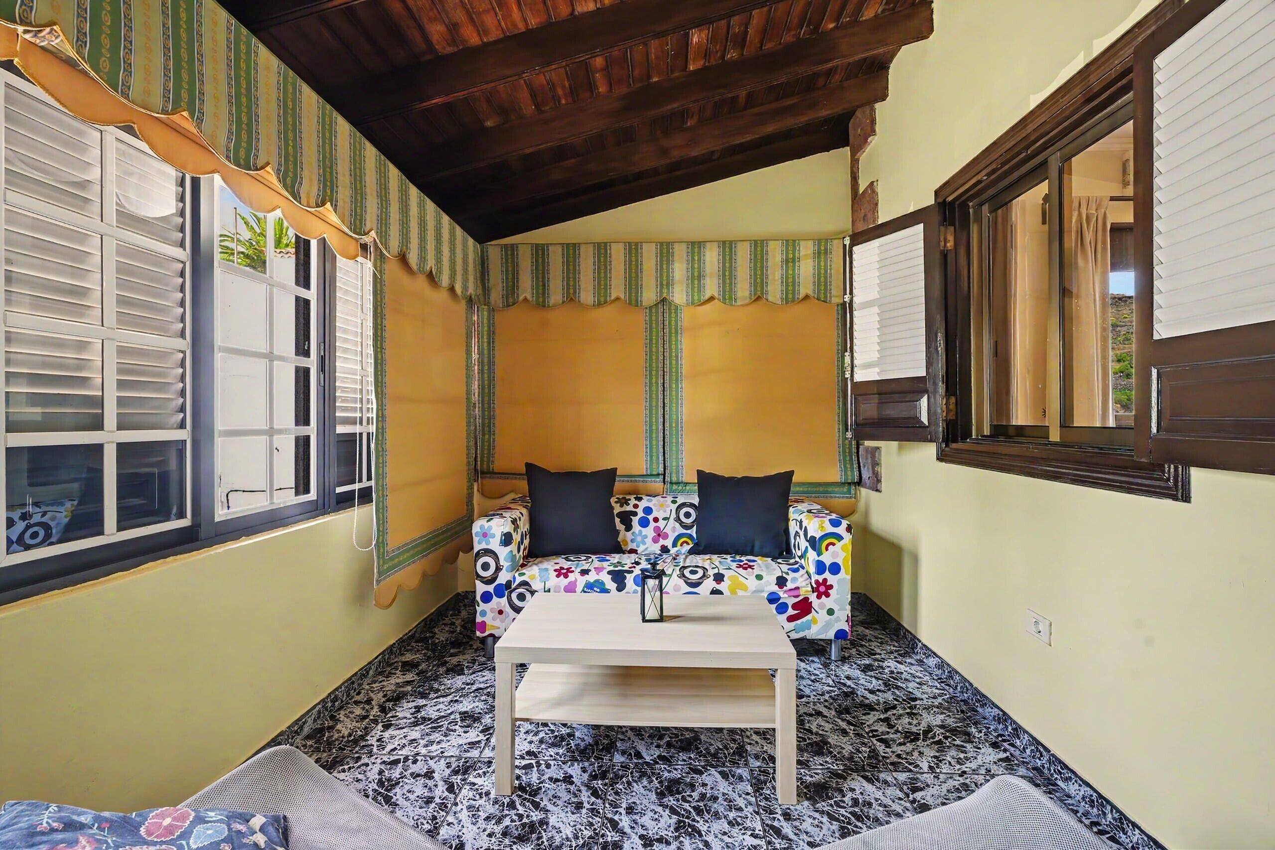 A room with a sofa, a table, and a window with shutters.