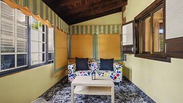 A room with a sofa, a table, and a window with shutters.