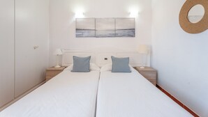 A double bed with two pillows, a bedside table with a lamp, a wall-mounted mirror, and a painting above the bed. - Casa Perla – Terrace & Pool in the Heart of Playa de Santiago (Playa de Santiago)