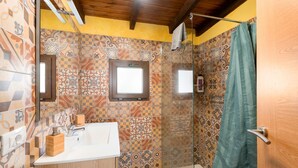 A bathroom with patterned tiles, a wooden door, a shower curtain, and a mirror.