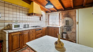 A kitchen with wooden cabinets, a microwave, a stove, and a brick wall.