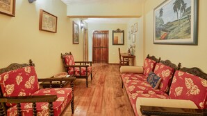 A room with a wooden floor, a sofa set, a dining table, chairs, and a door.