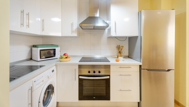 Una cocina compacta equipada con lavadora, microondas, horno y refrigerador.
