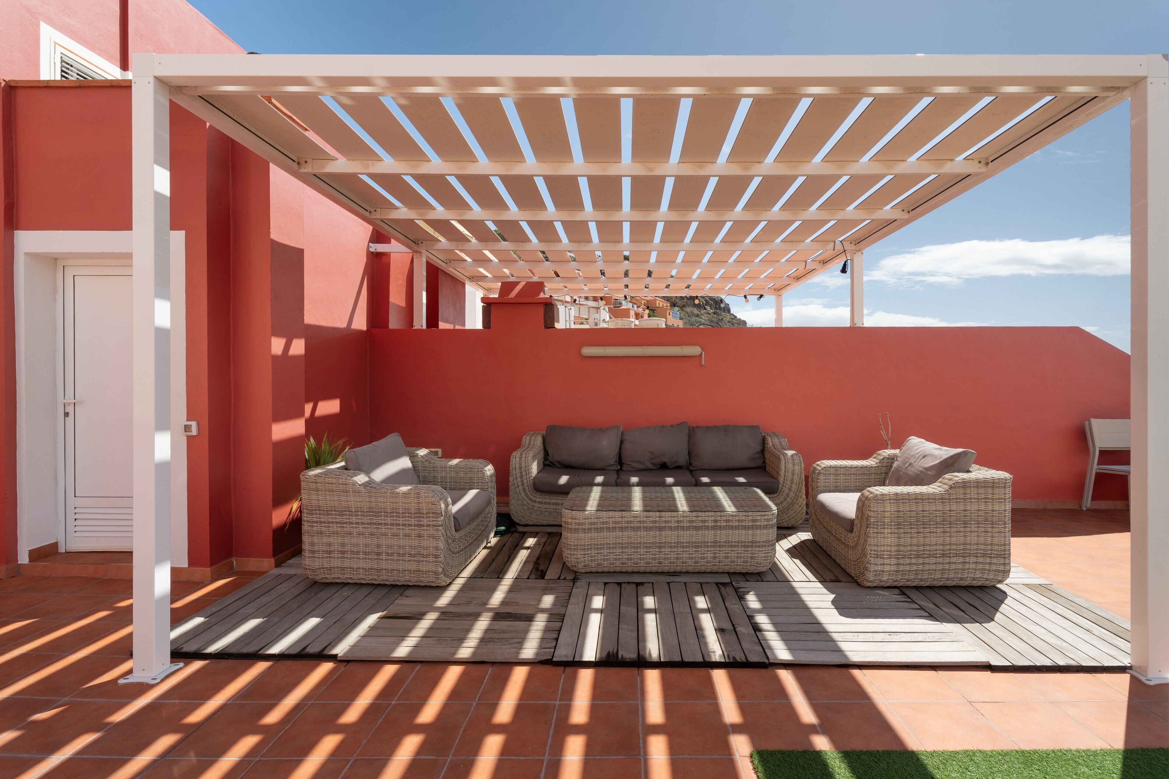 Un'area salotto esterna coperta con mobili in vimini e una pergola.