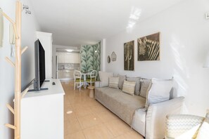 Un salon moderne comprenant un canapé, un téléviseur et un coin repas avec des chaises et une table.