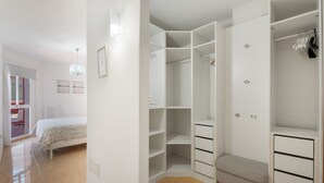 A bedroom with a bed, a walk-in closet with shelves and drawers, and a bathroom with a shower.