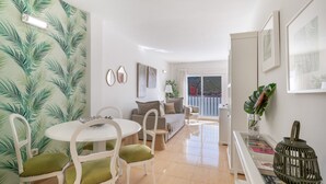 A modern living room with a dining area, a sofa, and a glass coffee table.