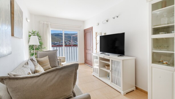 A living room with a sofa, television, and a cabinet with glass doors.