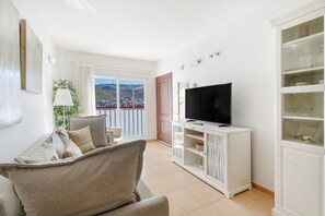 Una sala de estar con sofá, televisión y un aparador con puertas de cristal.