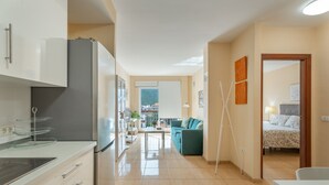 Cuina moderna amb nevera, fogó i zona de menjador. Al saló hi ha un sofà i un llit.