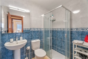 Un baño con lavabo, inodoro y cabina de ducha de cristal.