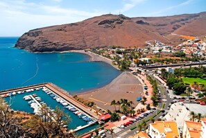 A coastal town with a marina, beach, and mountainous backdrop.
